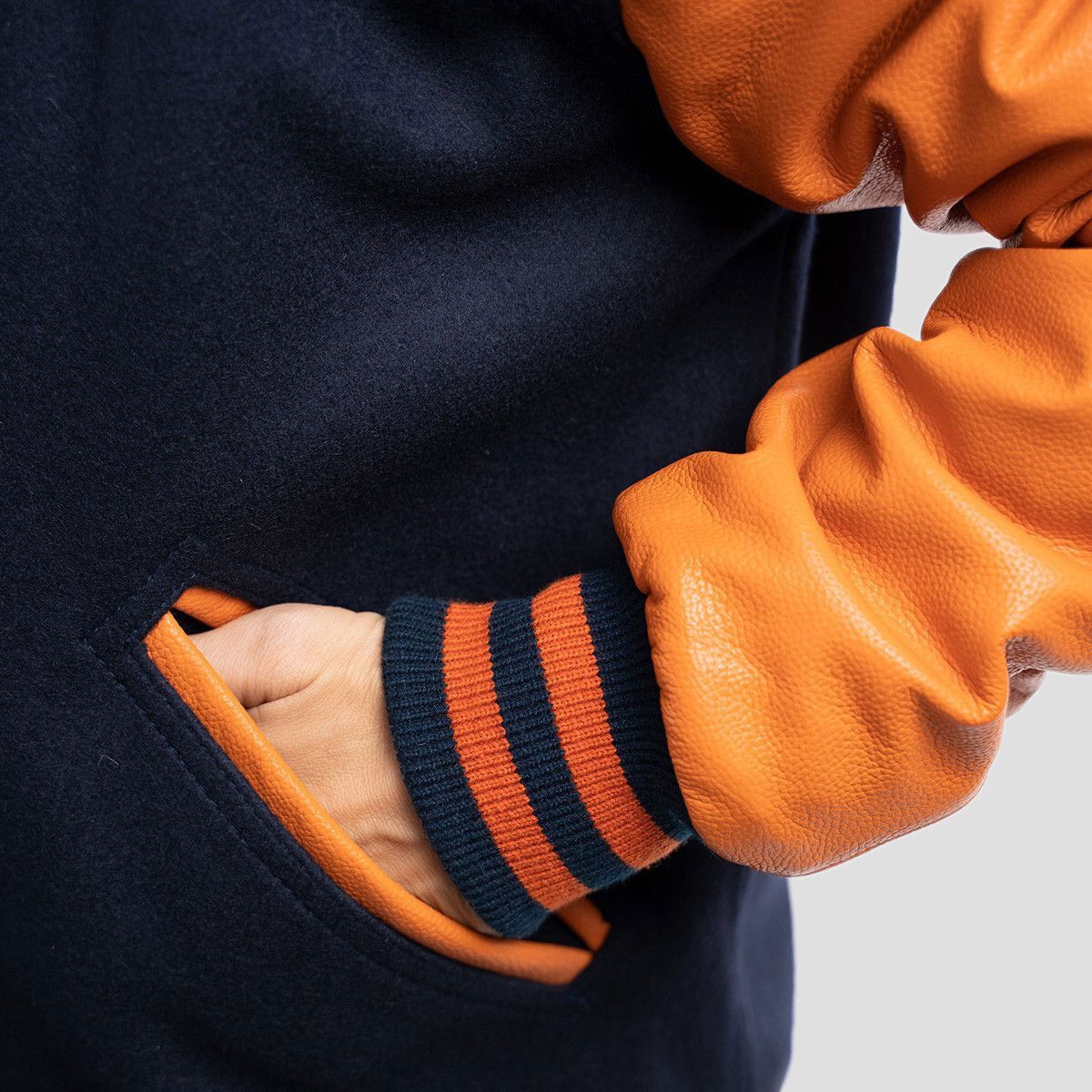 Chic royal blue wool letterman jacket with contrasting orange leather sleeves, designed for a modern athletic aesthetic