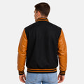 Back view of men’s black wool varsity jacket with gold leather sleeves and striped varsity waistband.