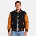 Men’s black and gold letterman jacket with premium wool body and gold leather sleeves on a gray background.