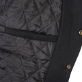 Close-up of a black quilted jacket with a gold button on a white background