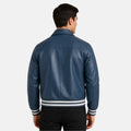 Man wearing a blue leather jacket with white stripes on a light gray background