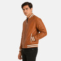 Men’s brown leather bomber jacket with striped ribbed cuffs and hem, front zip closure, worn over a black shirt.