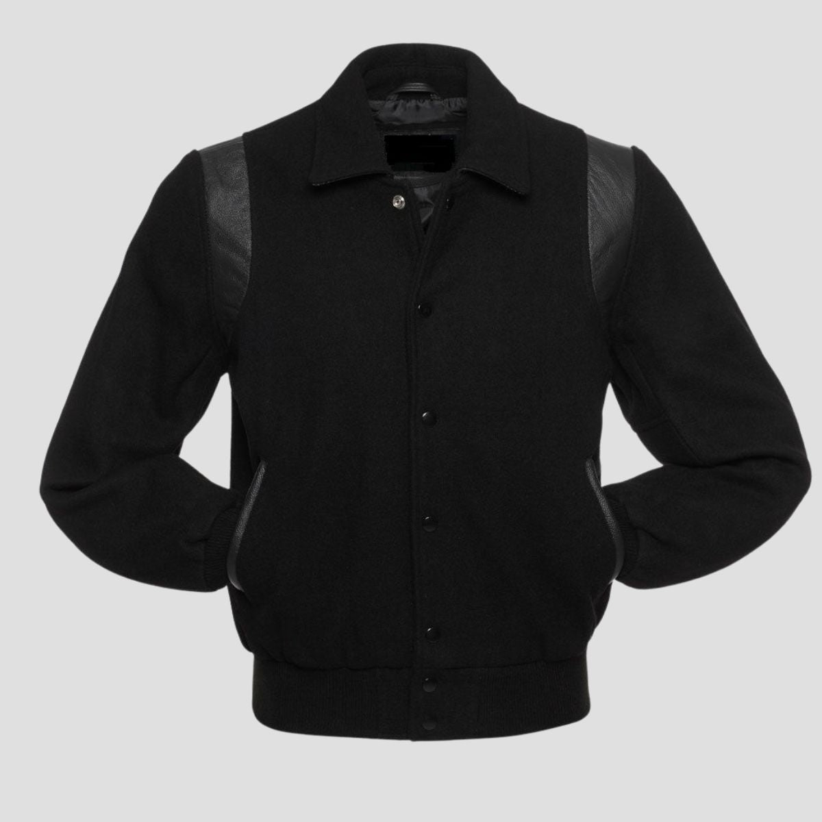 A vintage black wool college jacket with leather sleeves and snap button closure.