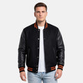 Man wearing a black varsity jacket with orange accents on a white background
