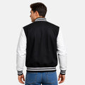 Man wearing a black and white varsity jacket on a plain background