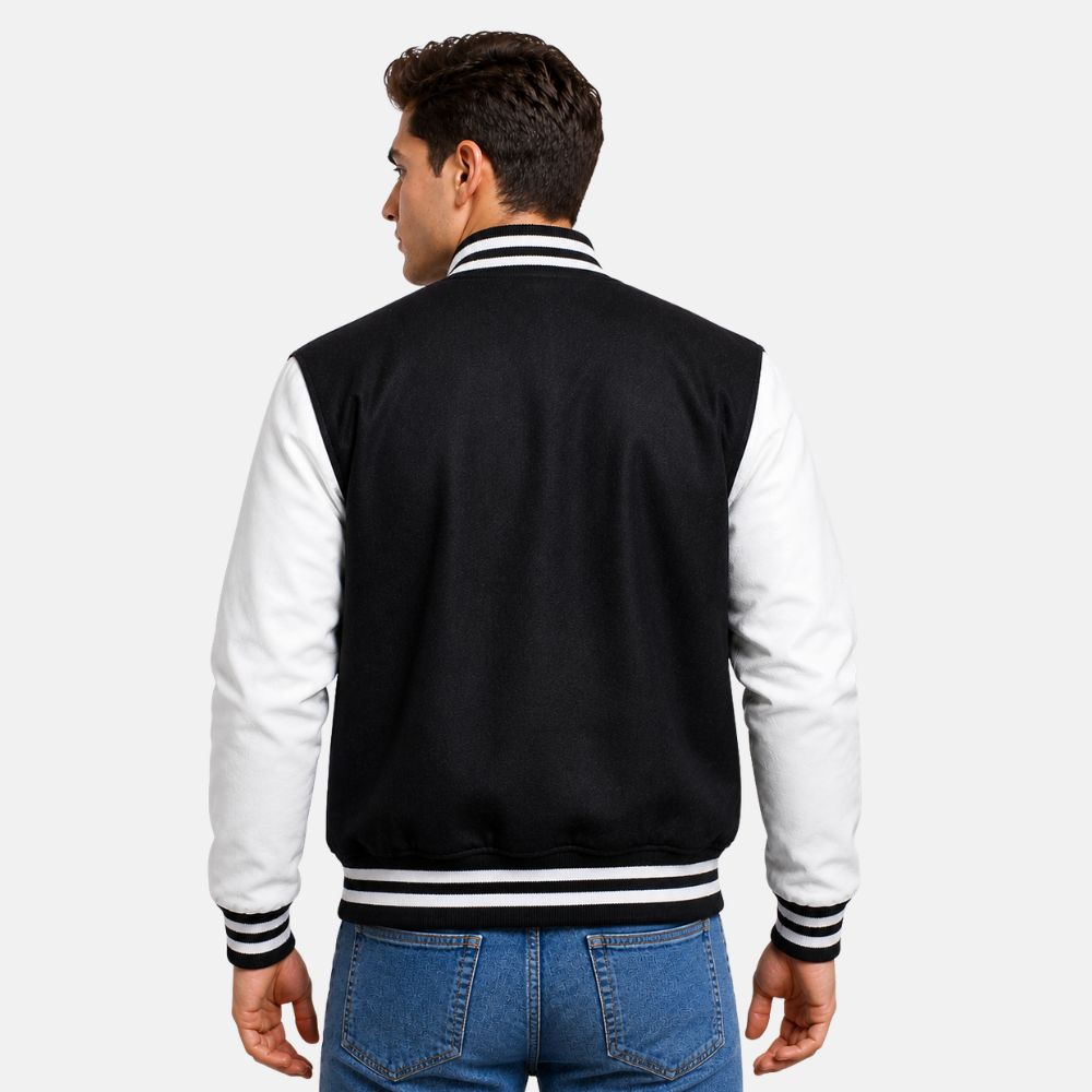 Man wearing a black and white varsity jacket on a plain background