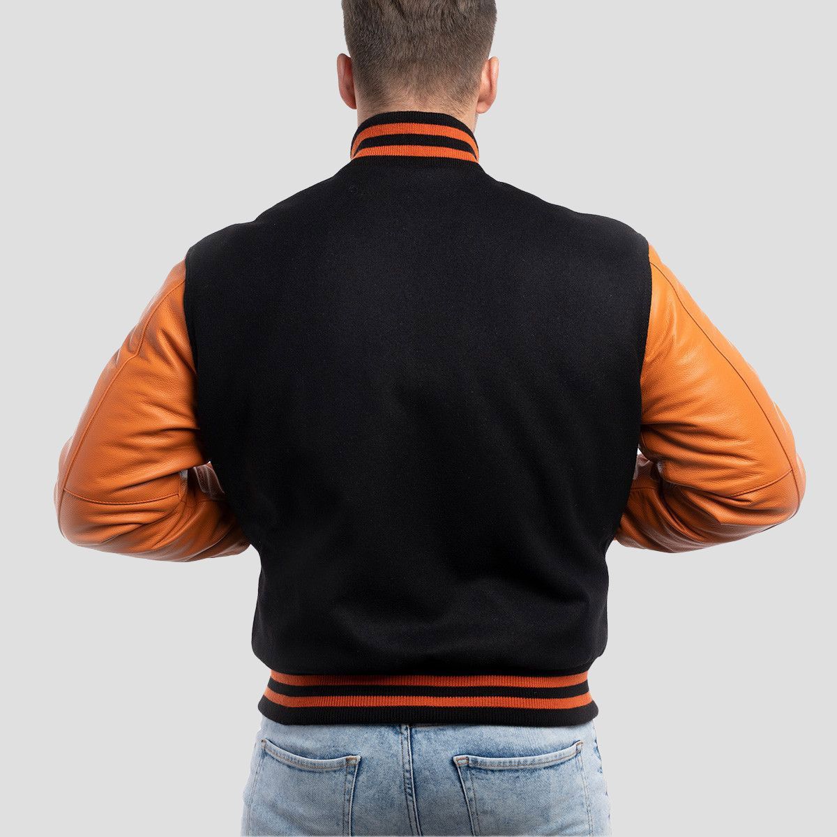 Men's black wool varsity jacket featuring vibrant orange leather sleeves, offering a sleek and classic fit