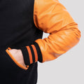 Black wool varsity jacket with eye-catching orange leather sleeves and a classic fit, ideal for casual or athletic wear