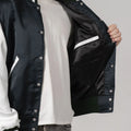 Varsity jacket in forest green satin with white sleeves, adding a fresh twist to a classic design