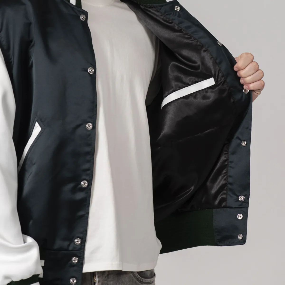 Varsity jacket in forest green satin with white sleeves, adding a fresh twist to a classic design