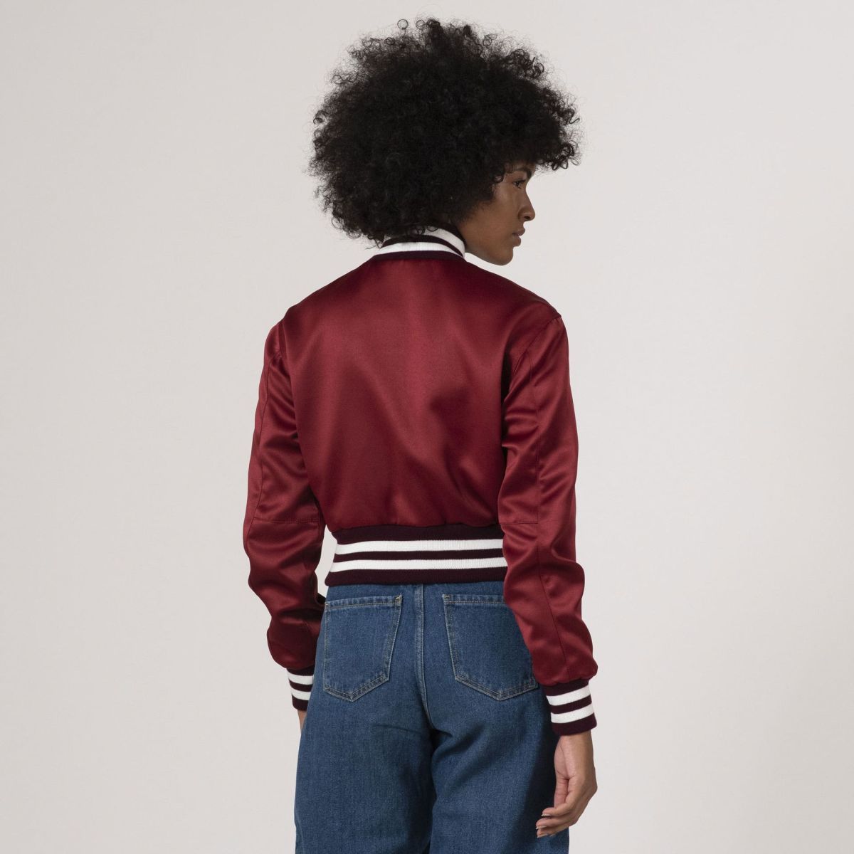 Fashionable maroon satin crop varsity jacket, combining luxe fabric with a sporty silhouette