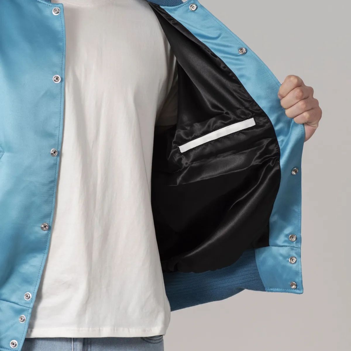 Stylish blue satin varsity jacket featuring white sleeves and trim, combining elegance and sporty flair