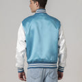 Chic modern blue varsity jacket with white sleeves and trim in satin, perfect for layering with streetwear