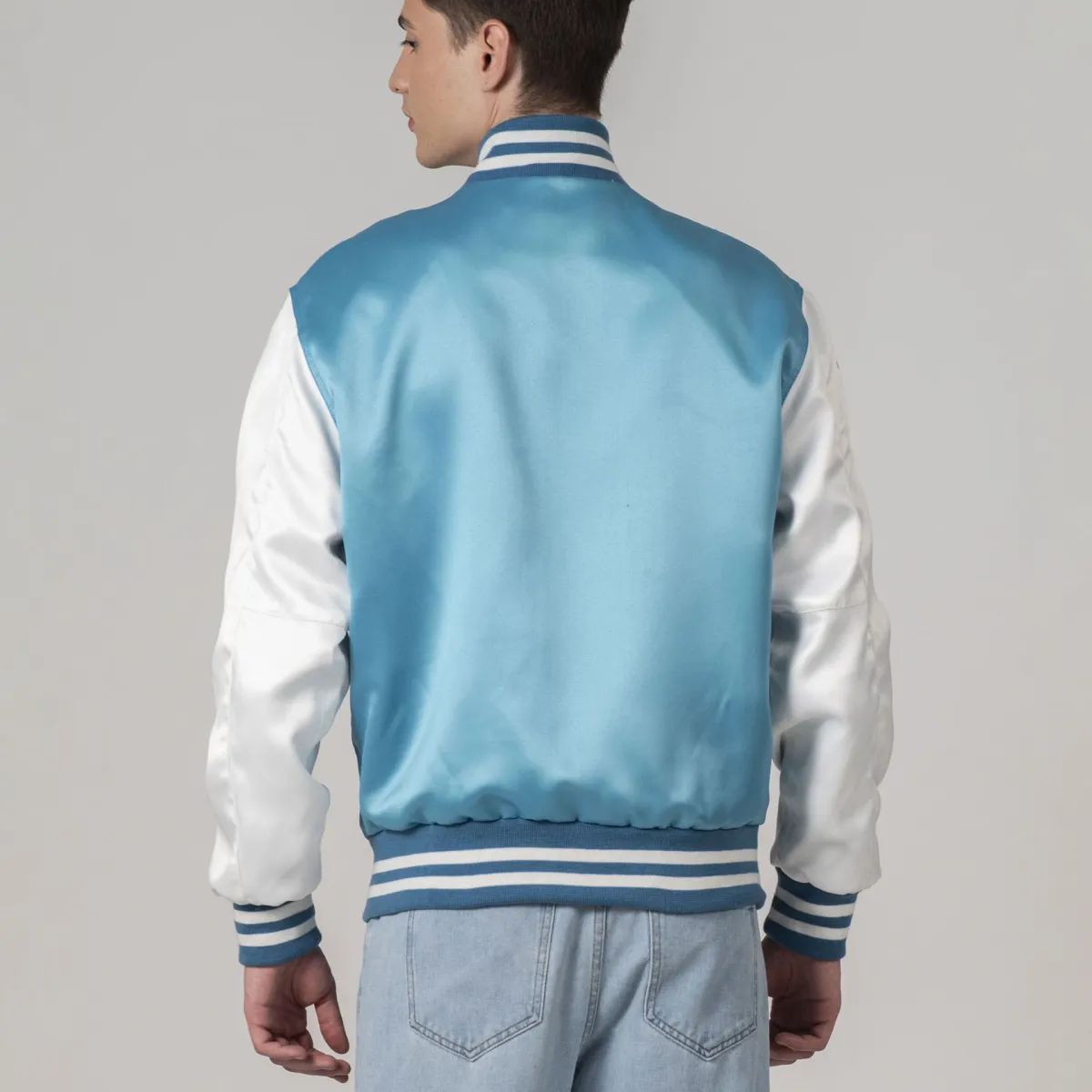 Chic modern blue varsity jacket with white sleeves and trim in satin, perfect for layering with streetwear