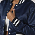 Fashionable navy blue crop top varsity jacket in satin, combining elegance with an athletic vibe