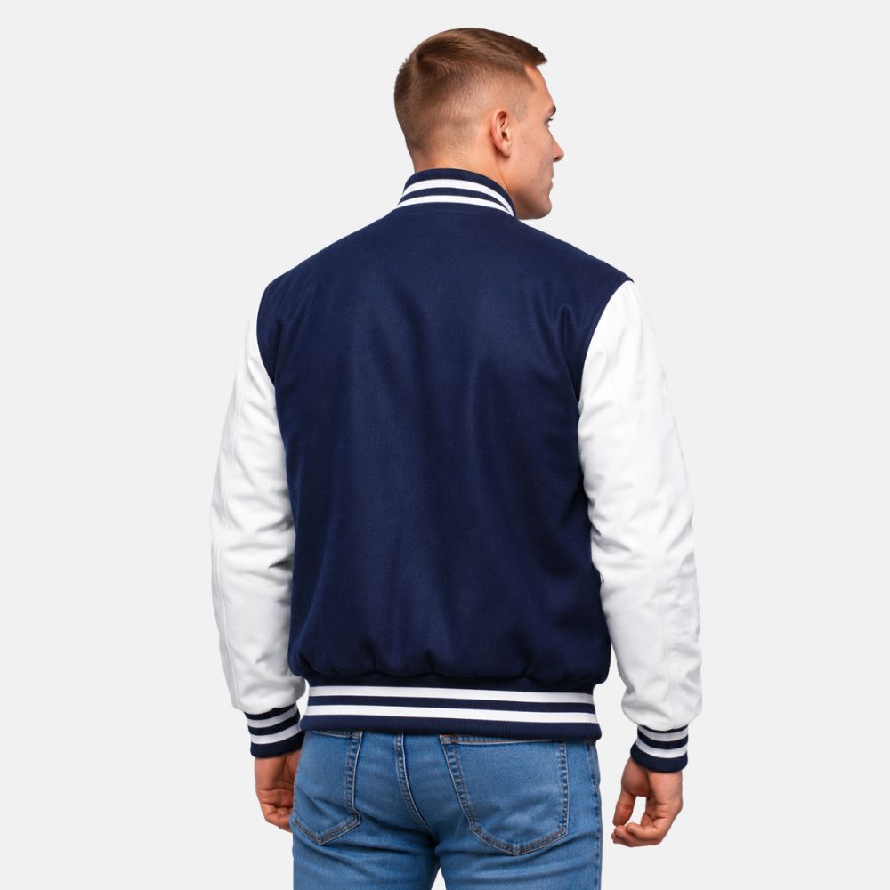 Man wearing a navy and white varsity jacket on a plain background