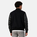 Person wearing a black bomber jacket with leather sleeves on a white background