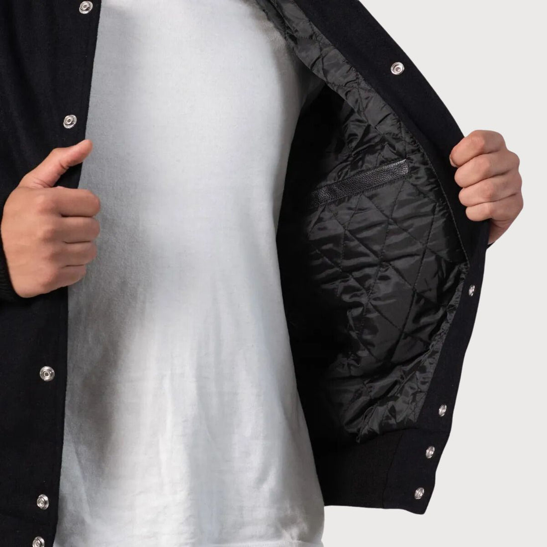 Stylish black wool varsity jacket with leather sleeves, tailored for a modern fit while maintaining classic elements