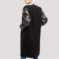 Trendy black wool varsity coat featuring leather sleeves, merging classic varsity charm with premium materials