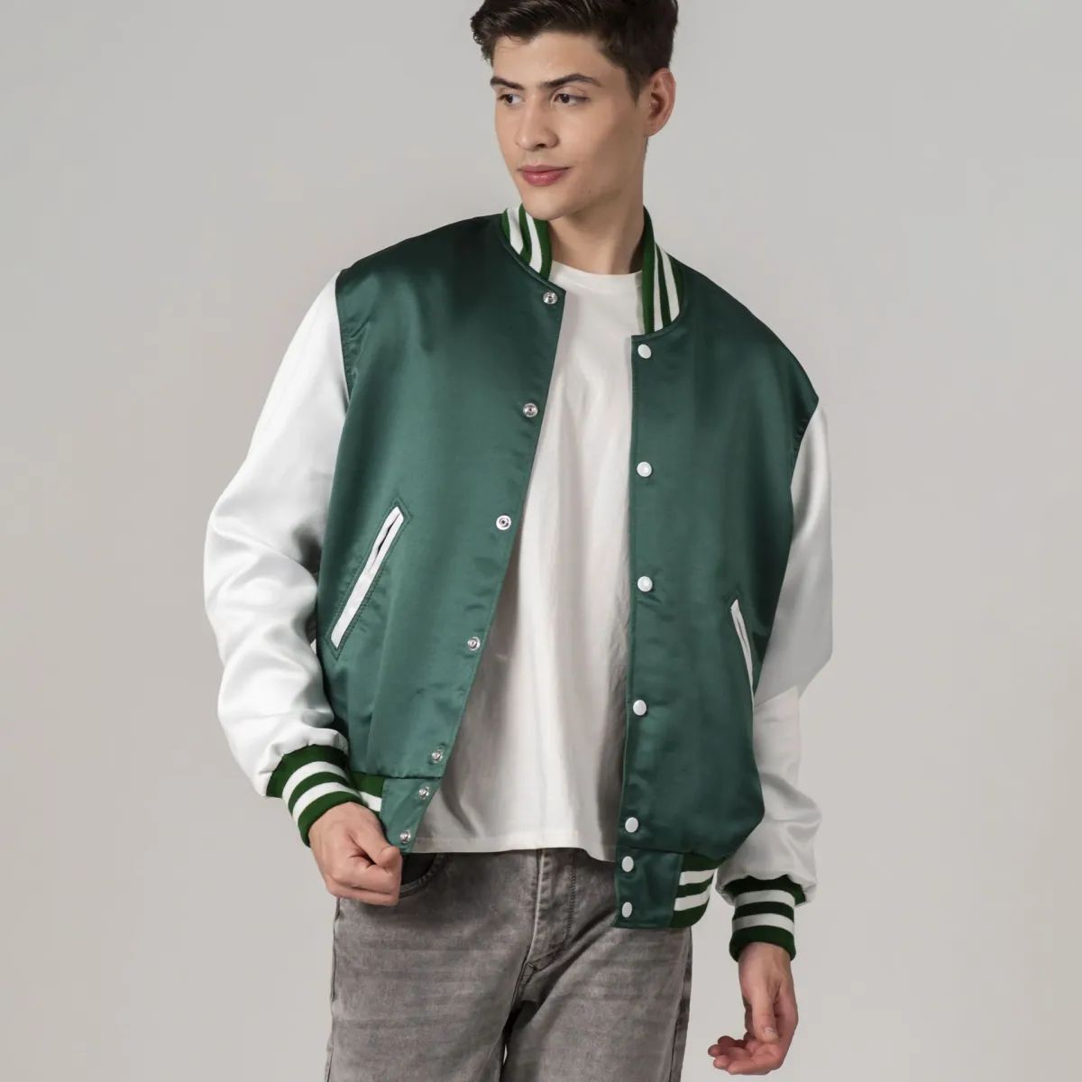 A male model wearing a Kelly green satin varsity jacket with white sleeves and a white collar, standing against a plain background.