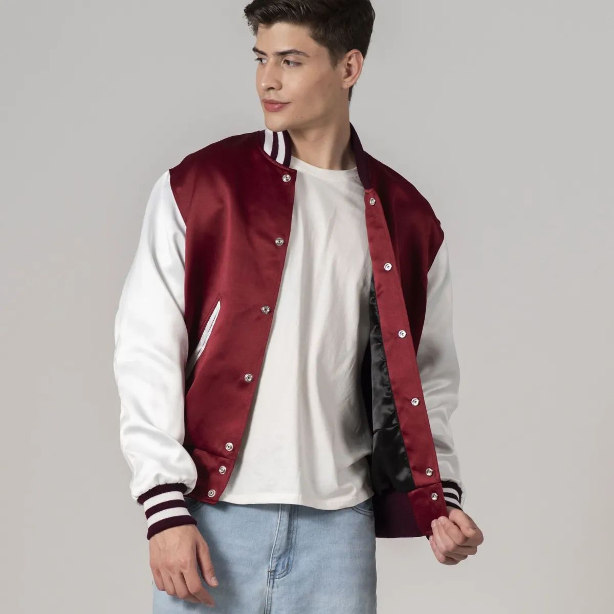 A male model wearing a maroon satin jacket with white sleeves, featuring a stand-up collar, knit cuffs, and white striping on the sleeves and hem.